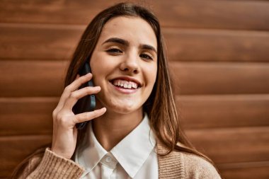 Genç İspanyol iş kadını gülümsüyor. Şehirdeki akıllı telefondan mutlu bir şekilde konuşuyor..