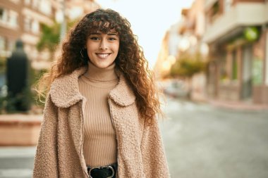 Genç İspanyol kadın gülümseyerek şehirde mutlu mesut dikiliyor.