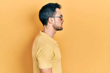 Gündelik kıyafetler ve gözlük takan genç İspanyol adam yan yan yan bakıyor, rahat poz veriyor kendine güvenen bir gülümsemeyle doğal bir yüz ifadesi sergiliyor.. 