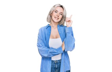 Yüzünde kocaman bir gülümseme olan sıradan kıyafetler giyen genç sarışın kız, kameraya el ve parmak ile bakıyor.. 