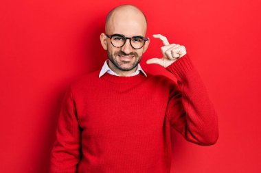 Genç kel bir adam günlük kıyafetler ve gözlük takıyor gülümsüyor ve kendinden emin el hareketleriyle hareket ediyor parmaklarıyla işaret yapıyor ve kameraya bakıyor. ölçüm kavramı. 