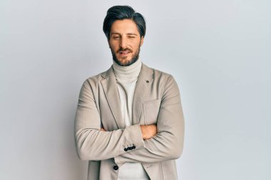 Kollarını kavuşturmuş genç İspanyol bir adam kameraya seksi bir ifadeyle bakıyor, neşeli ve mutlu bir yüzle.. 