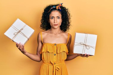 Elinde hediyeler tutan genç Latin kız şüpheci ve gergin, sorun yüzünden surat asıyor. negatif kişi. 