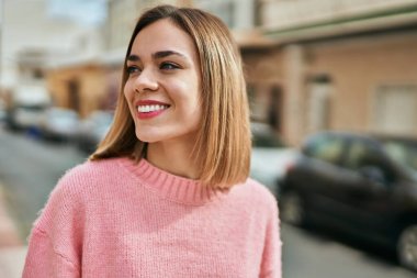 Genç beyaz kız gülümseyerek şehirde mutlu mesut duruyor..