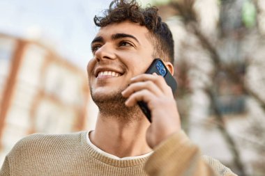 Genç İspanyol adam gülümsüyor. Şehirdeki akıllı telefondan konuşuyor.