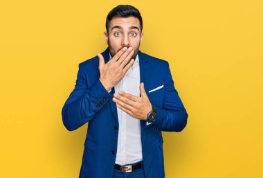 İş ceketi giyen genç İspanyol adam ağzını yanlışlıkla ellerle kapatırken şok oldu. gizli kavram. 