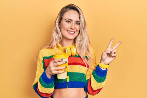 Vakker Blond Kvinne Som Drikker Kaffe Med Hodetelefoner Smiler Til – stockfoto