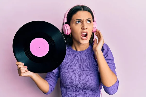 Jovem Hispânica Usando Fones Ouvido Segurando Disco Vinil Irritado Louco — Fotografia de Stock