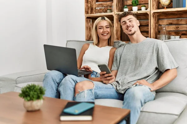 Evdeki Kanepede Oturan Genç Beyaz Çift Dizüstü Bilgisayar Akıllı Telefon — Stok fotoğraf