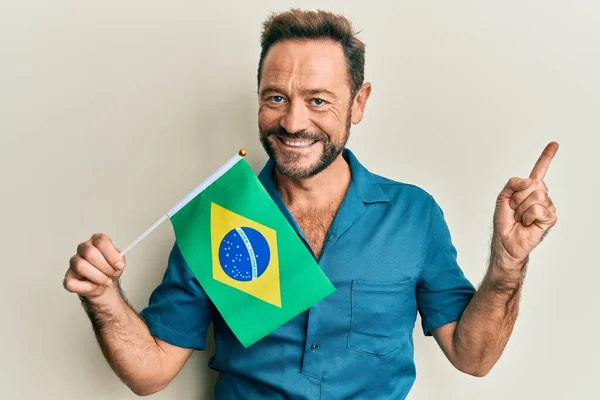 Muž Středního Věku Drží Brazilskou Vlajku Úsměvem Ukazující Rukou Prstem — Stock fotografie