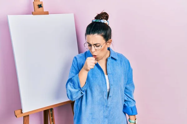 画家のイーゼルのそばに立つ若いヒスパニック系の女性は気分が悪く立ち 風邪や気管支炎の症状として咳をする ヘルスケアの概念 — ストック写真