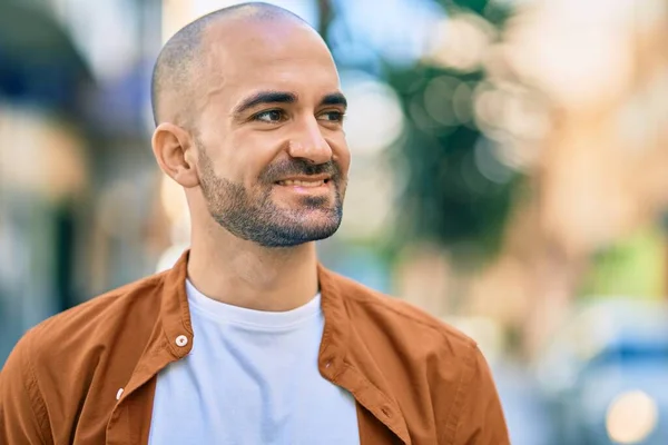 Young hispanic bald man smiling happy standing at the city.