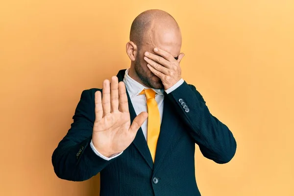 Young hispanic man wearing business suit and tie covering eyes with hands and doing stop gesture with sad and fear expression. embarrassed and negative concept.