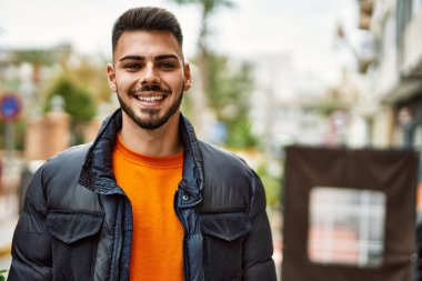 Yakışıklı, sakallı, neşeli ve kendine güvenen, kışlık palto giyen bir İspanyol.