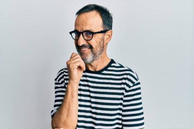 Orta yaşlı İspanyol bir adam gündelik kıyafetler ve gözlük takıyor gülümsüyor kameraya kollarını kavuşturup çenesinde elle bakıyor. Olumlu düşünmek. 