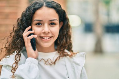 Güzel İspanyol kız gülümsüyor. Şehirdeki akıllı telefondan konuşuyor..
