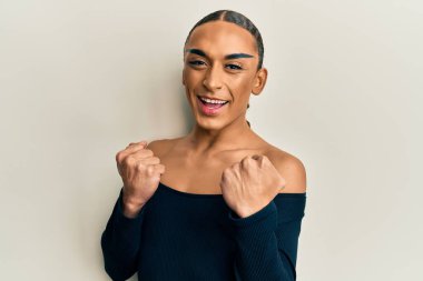 Makyaj yapan, uzun saçlı, kadın kıyafetleri giyen İspanyol bir adam. Başarılı olduğu için şaşırmış ve şaşırmıştı. Kolları havada, gözleri kapalıydı. 