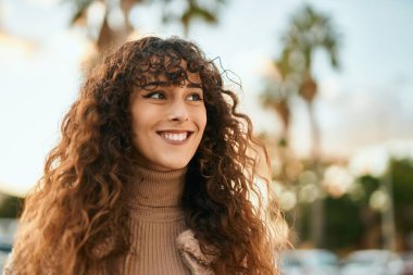 Genç İspanyol kadın gülümseyerek şehirde mutlu mesut dikiliyor.