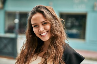 Genç İspanyol kadın gülümseyerek şehirde mutlu mesut dikiliyor..