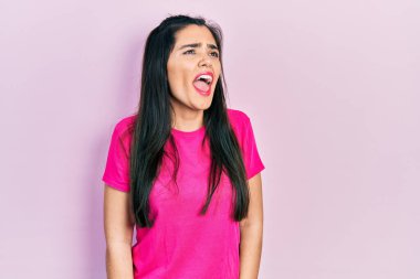 Genç İspanyol kız, günlük pembe t-shirt giyiyor kızgın ve kızgın bağırıyor sinirli ve öfkeli, öfkeyle bağırıyor. öfke ve agresif konsept. 
