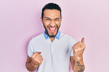 Beyaz tişörtlü İspanyol adam kolları havada ve gözleri kapalı bir şekilde başarıyı kutluyor ve şaşırıyor. 