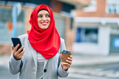 Genç Arap iş kadını akıllı telefon kullanıyor ve şehirde kahve içiyor..