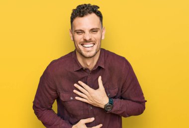 Gündelik kıyafetler giyen genç İspanyol adam gülümseyerek kahkahalarla gülüyor çünkü elleri vücutta olan komik, çılgın bir şaka.. 