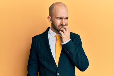 İş elbisesi giyen ve kravat takan genç İspanyol adam gergin ve elleri ağızdan tırnak yerken gergin görünüyor. anksiyete. 