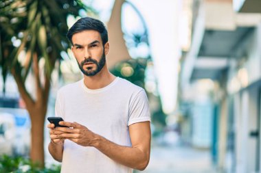 Şehirde akıllı telefon kullanan ciddi bir suratı olan genç bir İspanyol..