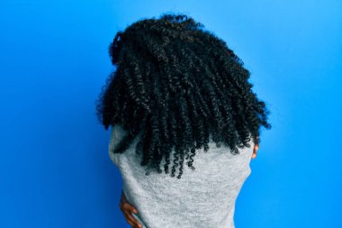 Afro saçlı, kışlık süveter giyen, mutlu ve pozitif bir şekilde sarılan Afro-Amerikalı bir kadın. Sevgi ve özgüven. 