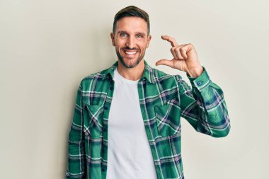 Sakallı, sıradan giyinen, gülümseyen, kendine güvenen, el hareketleriyle hareket eden, parmaklarıyla işaret eden ve kameraya bakan yakışıklı bir adam. ölçüm kavramı. 