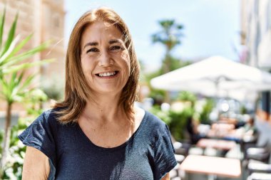 Orta yaşlı İspanyol kadın güneşli bir günde mutlu bir şekilde gülümsüyor.