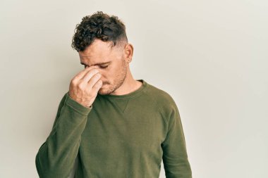 Günlük kıyafetler giyen genç İspanyol adam yorgun burnu ve gözleri ovuşturup yorgun ve baş ağrısı çekiyor. Stres ve hüsran kavramı. 