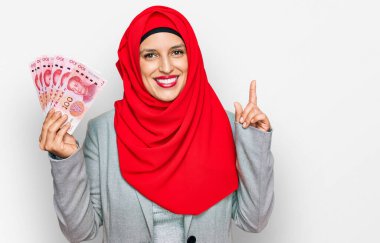 İslami tesettür takan güzel İspanyol kadın elinde Çin Yuan banknotları ile bir fikir ya da soru işareti ile şaşırdı. 