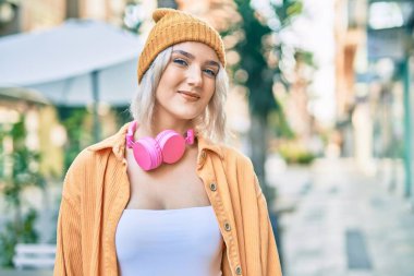 Şehirde kulaklık takan genç sarışın kız..