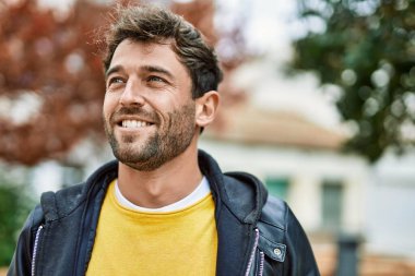 Yakışıklı, sakallı, açık havada mutlu gülümseyen bir İspanyol.