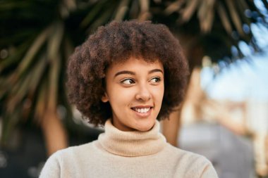 Genç İspanyol kız gülümseyerek şehirde mutlu mesut dikiliyor..