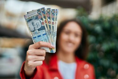 Genç İspanyol kadın gülümsüyor. Mutlu bir şekilde Peru banknotlarını şehirde tutuyor..