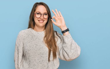 Gündelik süveter giyen ve gülümseyen genç sarışın kadın el ve parmaklarıyla 