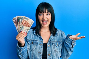 Genç İspanyol kadın elinde Mısır banknotları tutarak başarıyı mutlu bir gülümsemeyle kutluyor ve kazanan el kaldırarak ifade ediyor. 