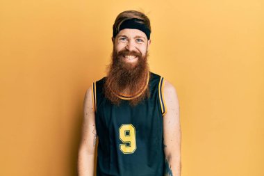 Kızıl saçlı, uzun sakallı basketbol forması giyen yüzünde güzel bir gülümseme olan bir adam. şanslı kişi. 