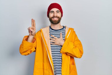 Sakallı, sarı yağmurluk giyen, göğsünde ve parmakları havada küfür eden, sadakat yemini eden beyaz bir adam. 