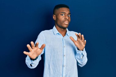 Sıradan kıyafetler giyen, korku ifadesinden korkan ve dehşete düşmüş genç Afro-Afrikalı Amerikalı adam el kol hareketi yapmayı kes, şok içinde bağır. panik konsepti. 