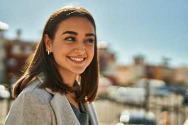 Genç İspanyol kız gülümseyerek şehirde mutlu mesut dikiliyor..