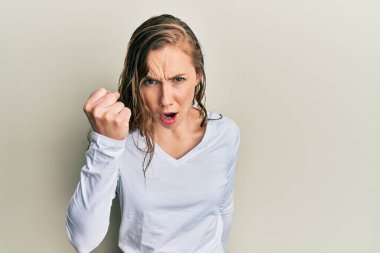 Genç sarışın kadın, kızgın ve kızgın. Öfkeyle bağırırken yumruğunu kaldırıyor ve öfkeleniyor. öfke ve agresif konsept. 