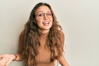 Gündelik kıyafetler ve gözlük takan genç İspanyol kız güler yüzlü kollar açık, dostça karşılama, olumlu ve kendinden emin selamlar. 