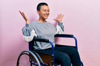 Tekerlekli sandalyede oturan kısa saçlı güzel İspanyol kadın başarı için deli ve deli gibi kutlama yapıyor kolları havada ve gözleri kapalı heyecanla bağırıyor. Kazanan konsept 