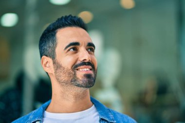 Genç İspanyol adam gülümseyerek şehirde mutlu mesut dikiliyor..