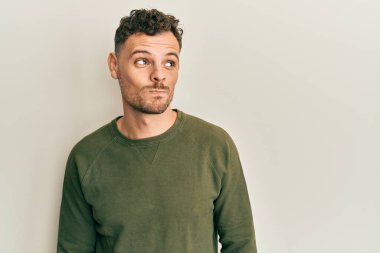 Gündelik kıyafetler giyen genç İspanyol adam gülümseyip yan tarafa bakıyor ve düşünüyor.. 