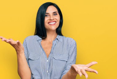 Gündelik kıyafetler giyen, neşeli gülümseyen, dostça kollarını açmış, olumlu ve kendinden emin bir şekilde selamlayan beyaz bir kadın. 